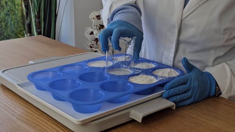 Firmly pressing the shower steamer mixture into a silicone muffin mould Firmly pressing the shower steamer mixture into a silicone muffin mould