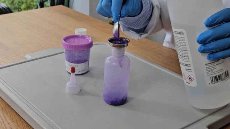 Preparing purple mica and isopropyl alcohol in a squeeze bottle for decorating Preparing purple mica and isopropyl alcohol in a squeeze bottle for decorating
